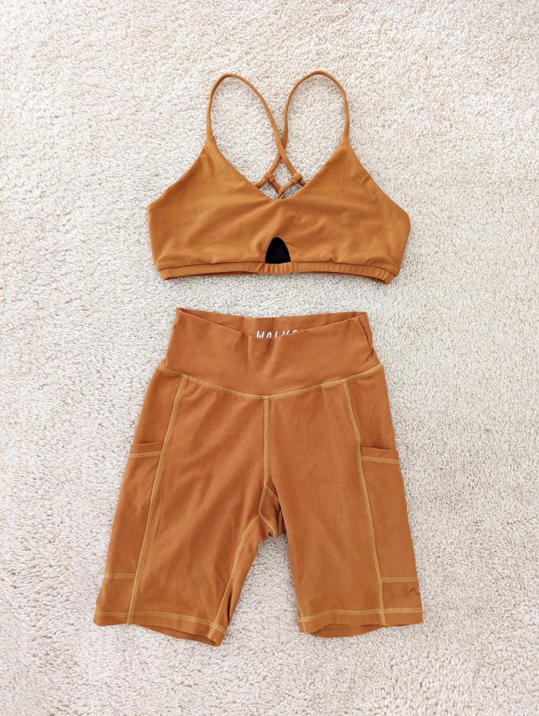 Wolven Pocket Bike Short and Crisscross Bra in turmeric lying flat on the carpet