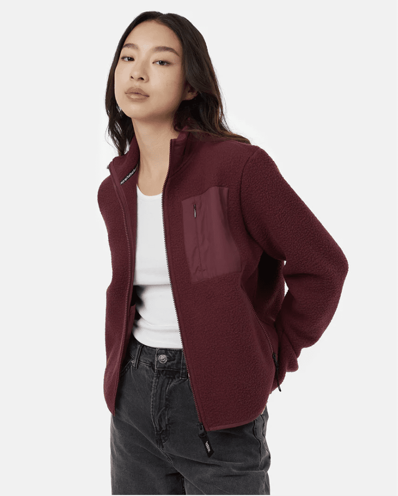 Asian woman wearing a burgundy fleece jacket and black pants with a white top