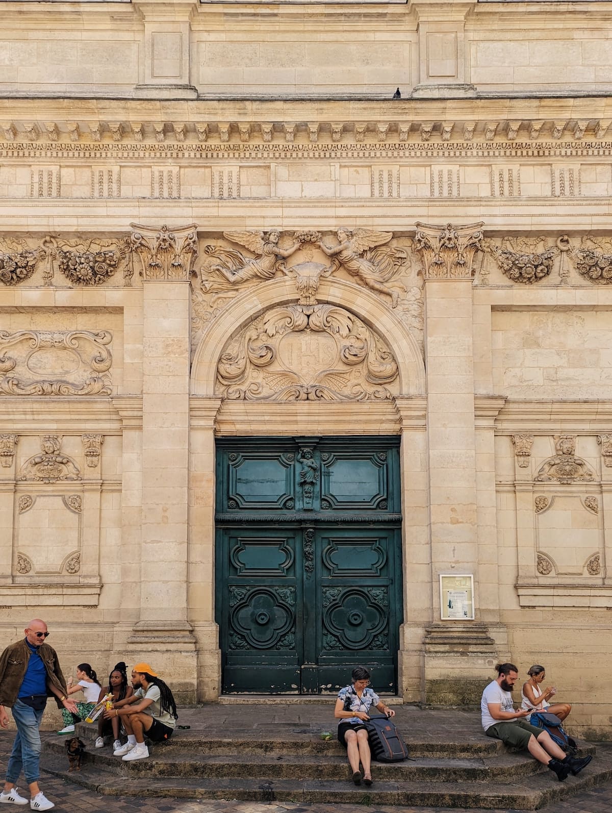 Historic church in Bordeaux with intricate, yellow stone exterior and deep green doors