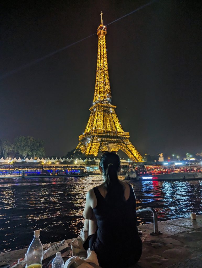 Silhouette of Jingwen looking at the Eiffel Tower at night with our picnic in the foreground