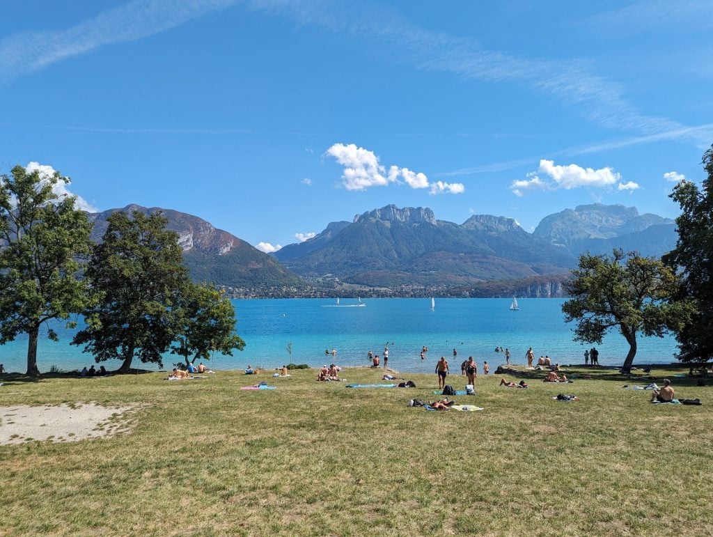 Grassy beach with turquoise water and mountains in the background