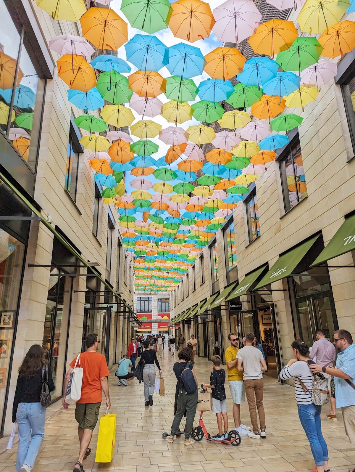 Bright umbrellas hanging from the sky in an alleyway