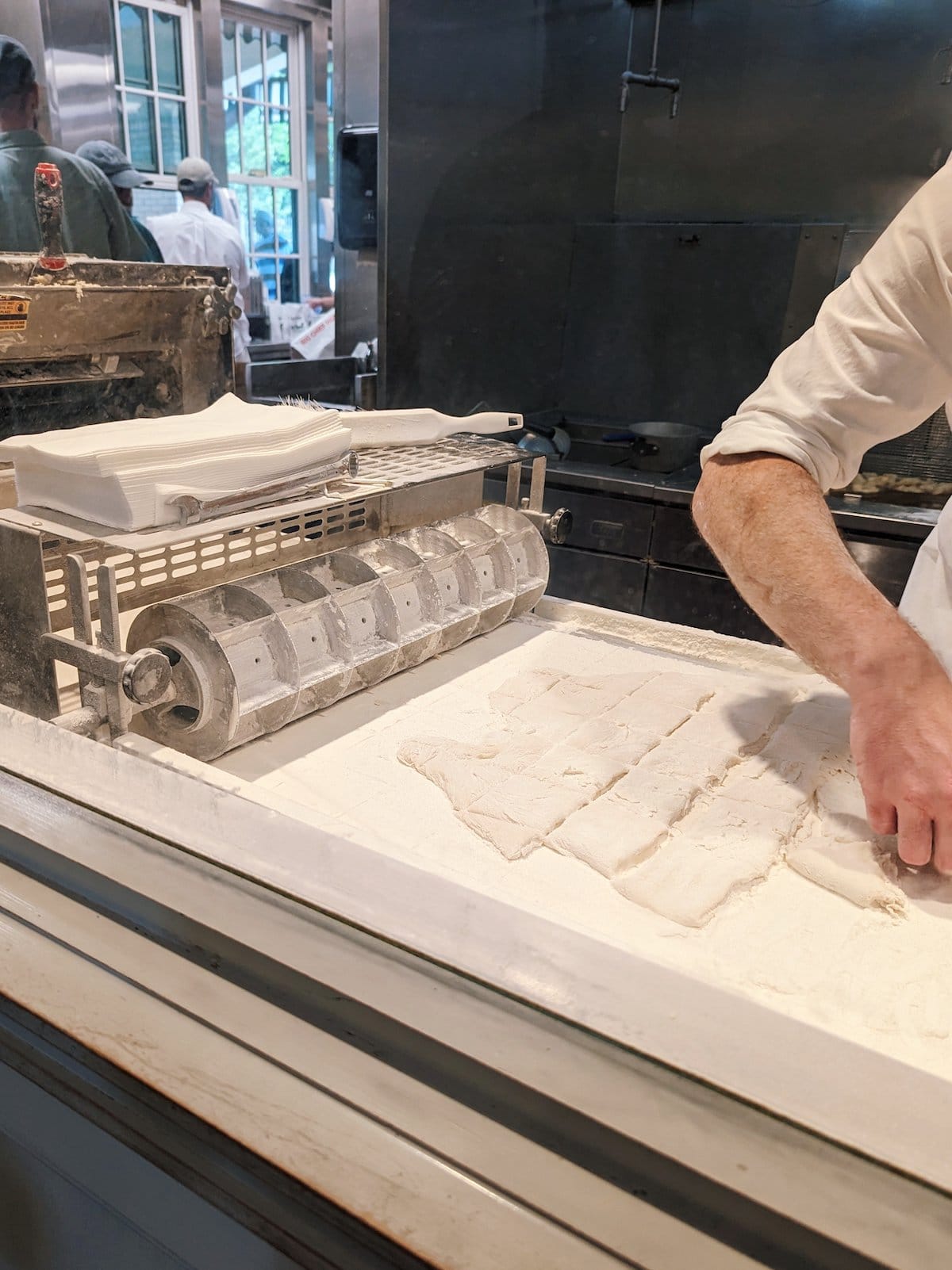 Person making beignets with cut-out dough squares
