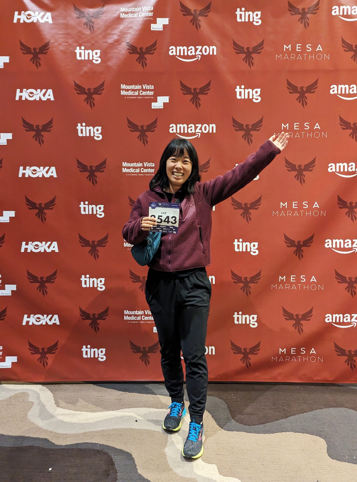 Me holding my race number in front of a photo wall at the Mesa Half Marathon expo