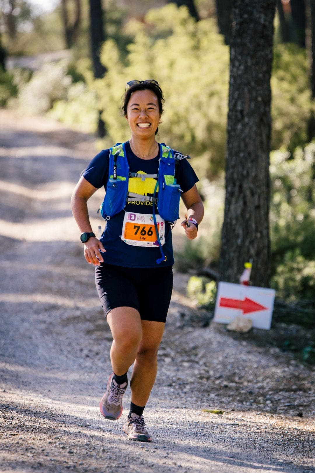Me smiling and running downhill in the forest on a gravel path