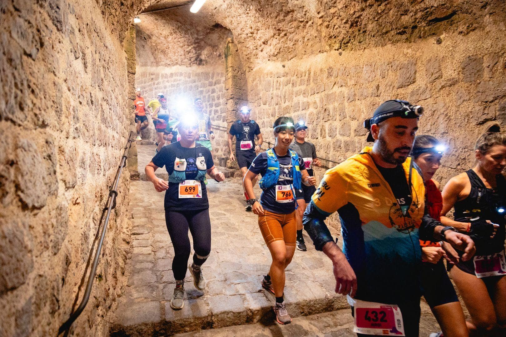 Runners with headlamps going through a tunnel