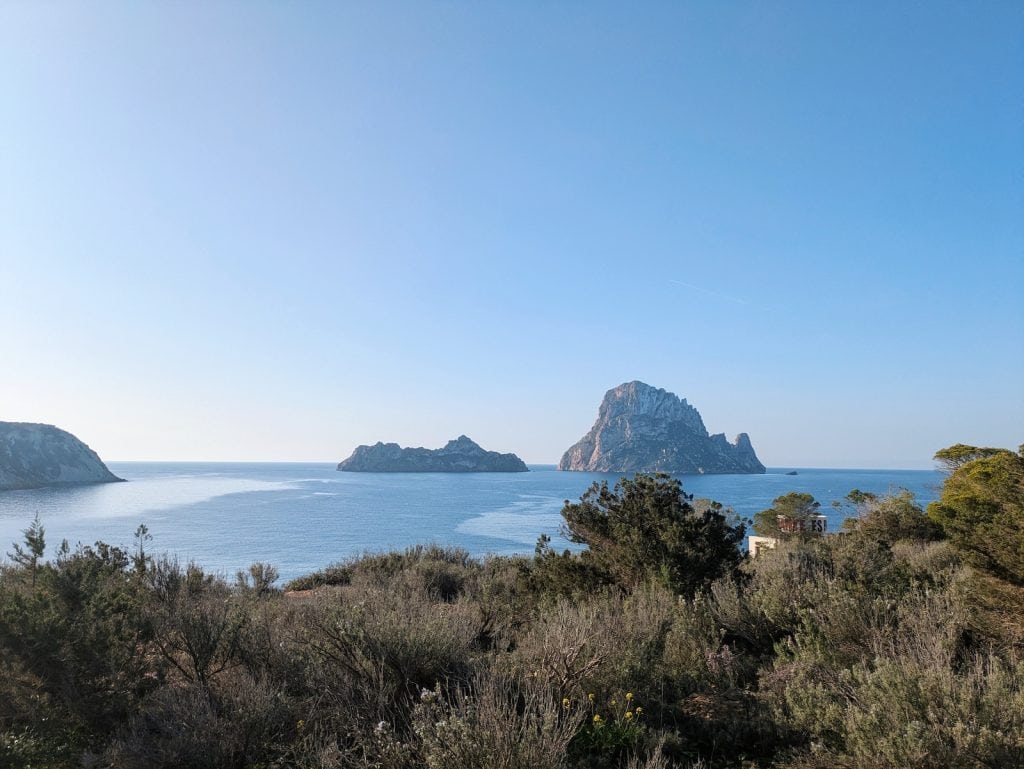 Beautiful view at the start line of the second day of 3 Dias Trail Ibiza. Blue, clear skies and some small islands are in the distance and some grass in the foreground