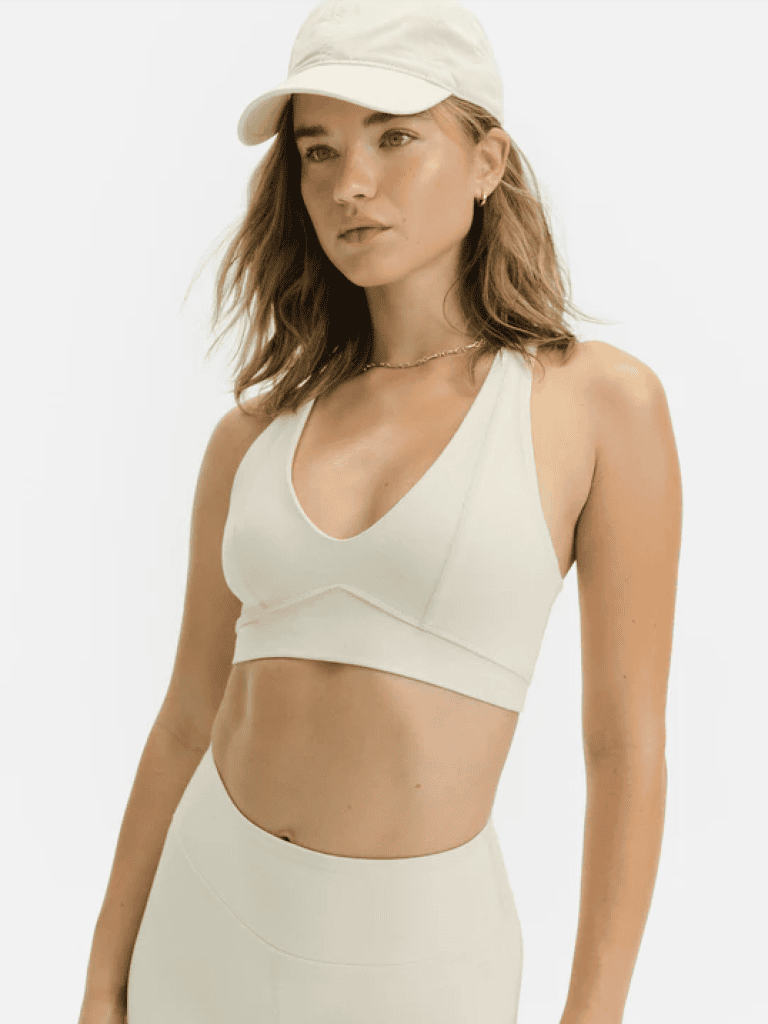 Photo of a woman with dirty blonde hair wearing a V-neck sports bra in white