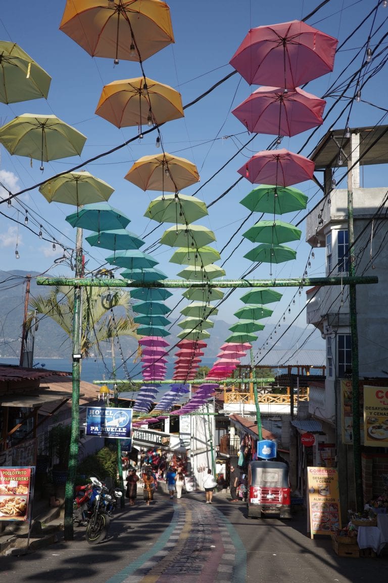 Colorful umbrella street in San Juan la Laguna winding down to the water