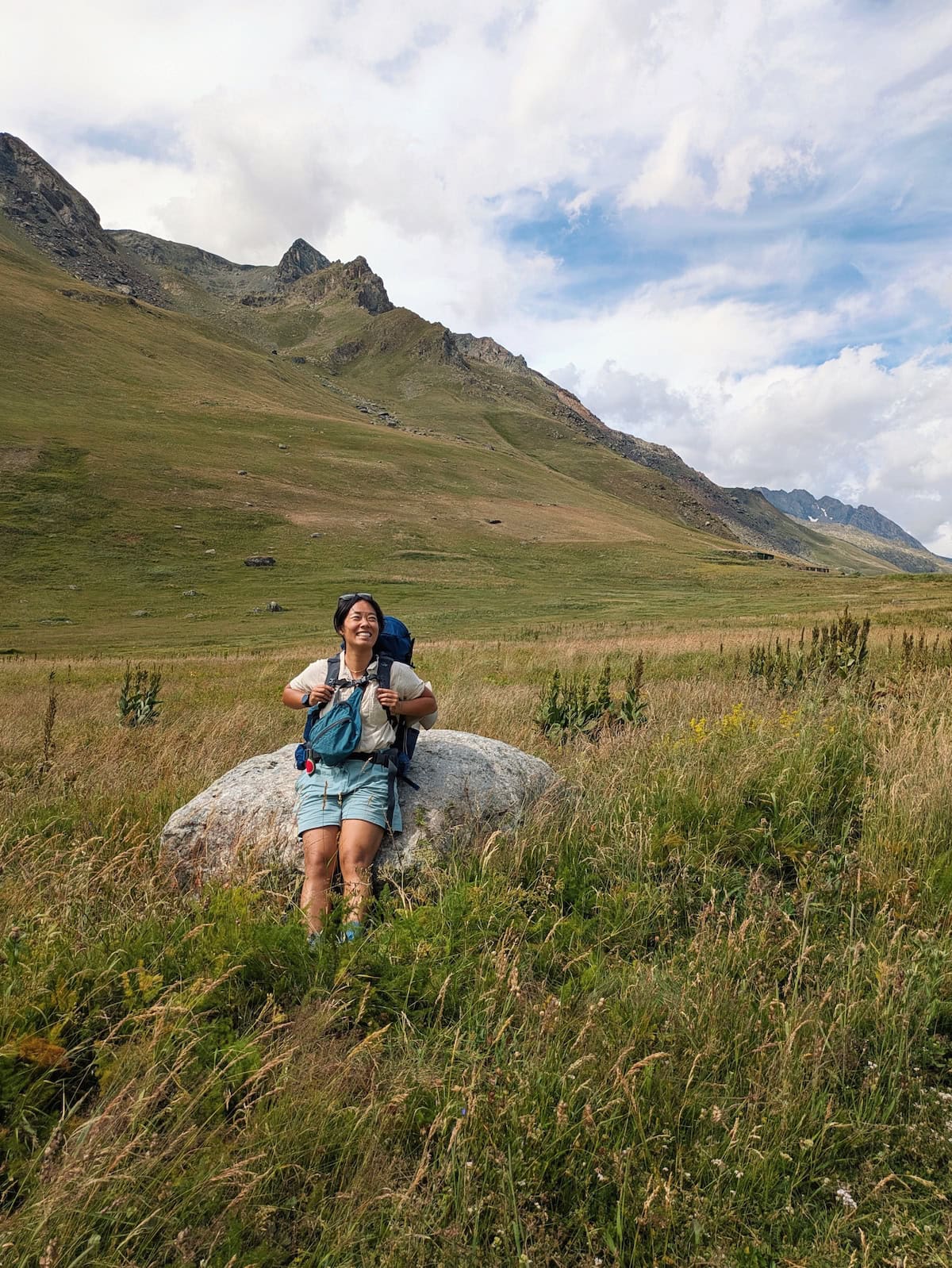 Me sitting on a rock in a grassy field on Day 1 of the GR54