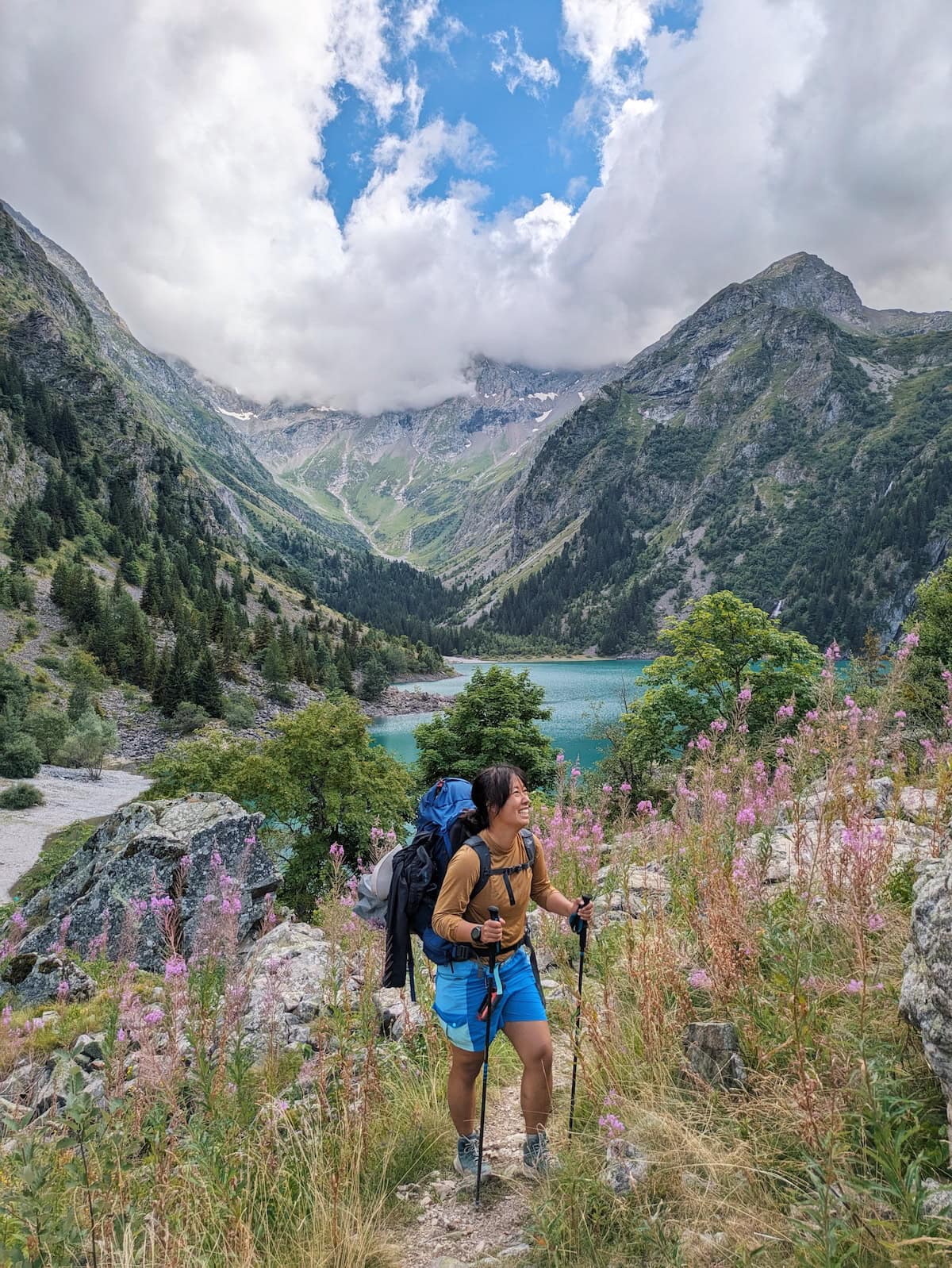 Me posing with wildflowers around me and Lac du Lauvitel behind me