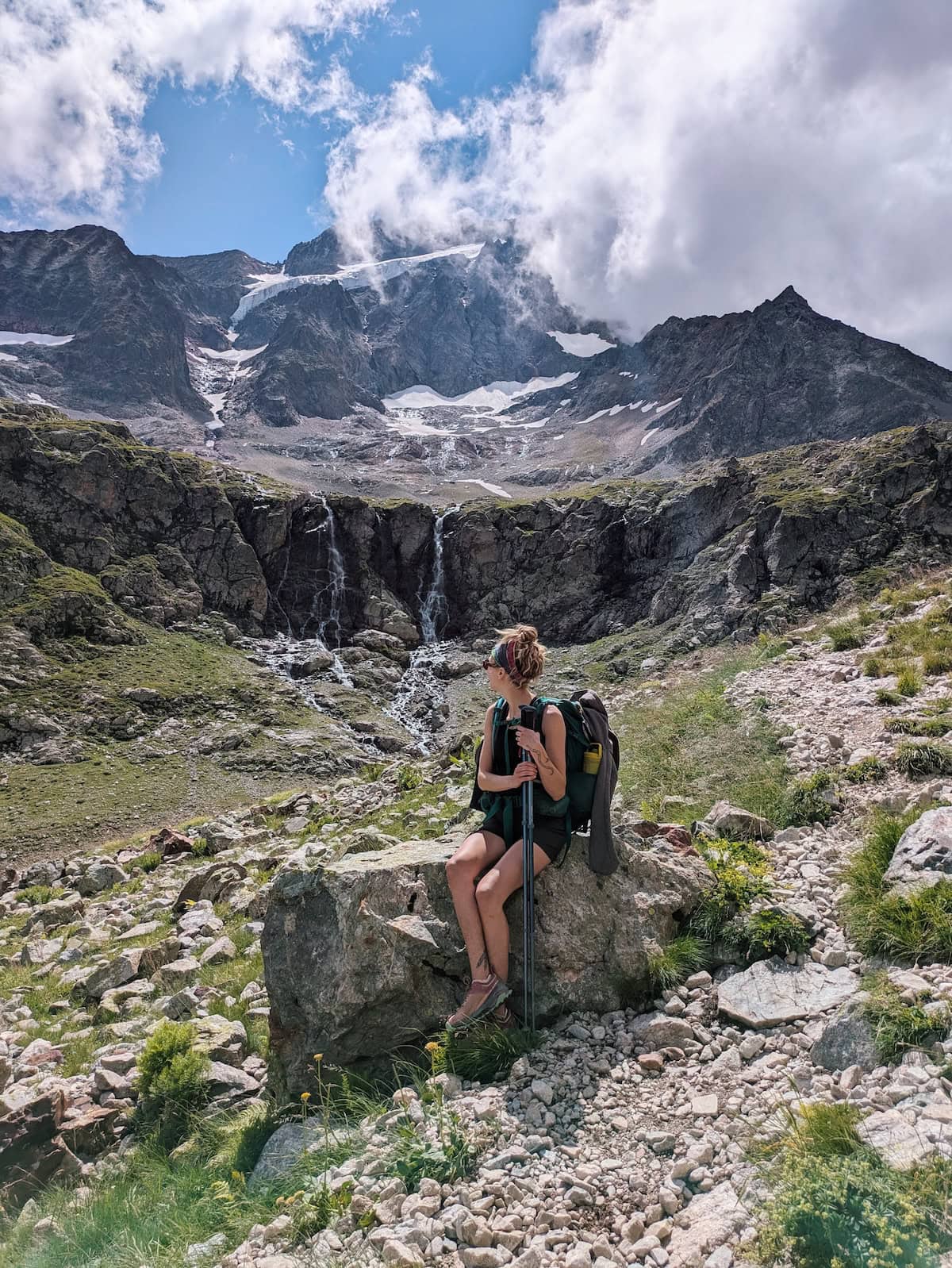 Tessa sitting on a rock with glaciers and waterfalls in the background
