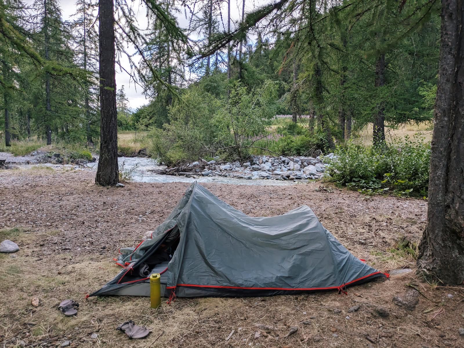 Our campsite with a gray tent by the stream in the woods