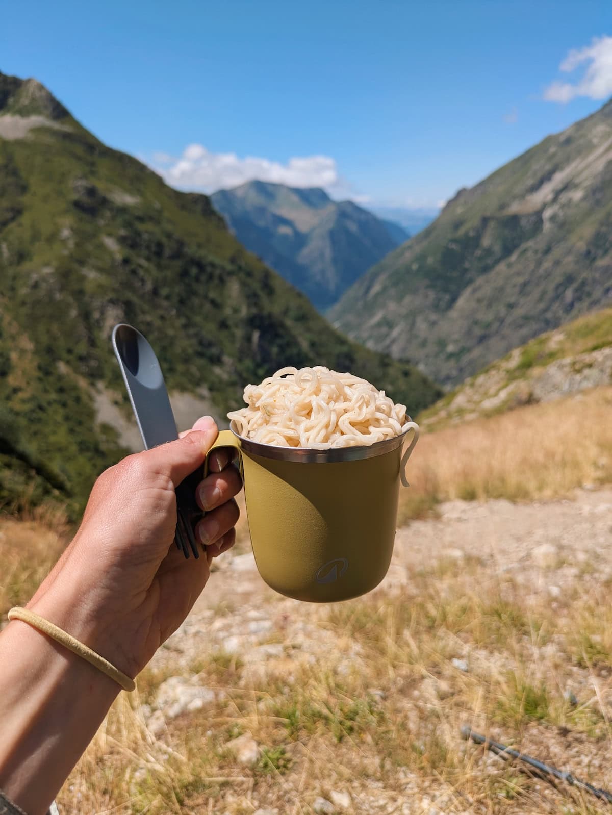 Trail ramen in a metal cup with mountains in the background