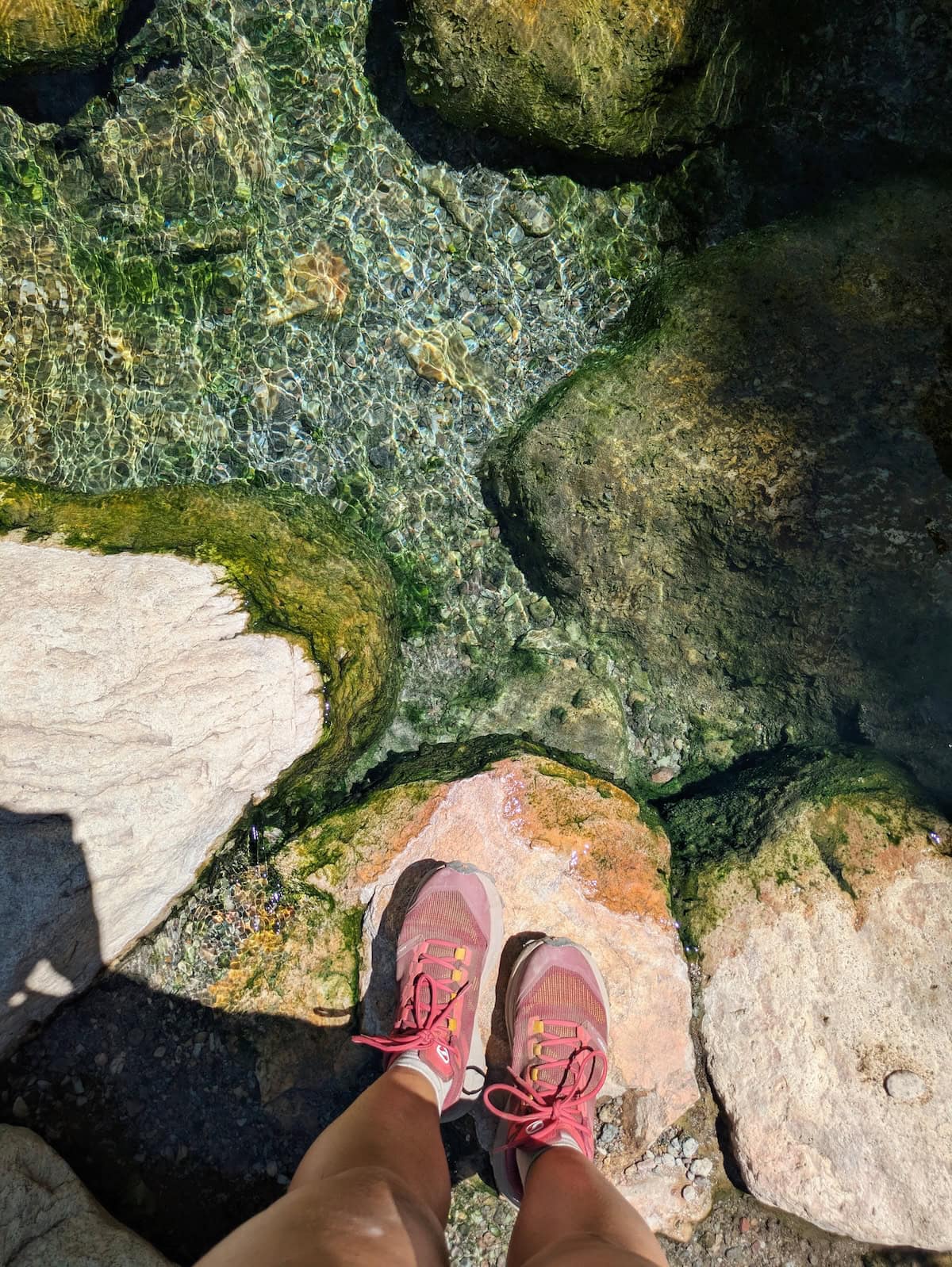 Point of view shot of my trail runners on a rock with the clear water beneath it